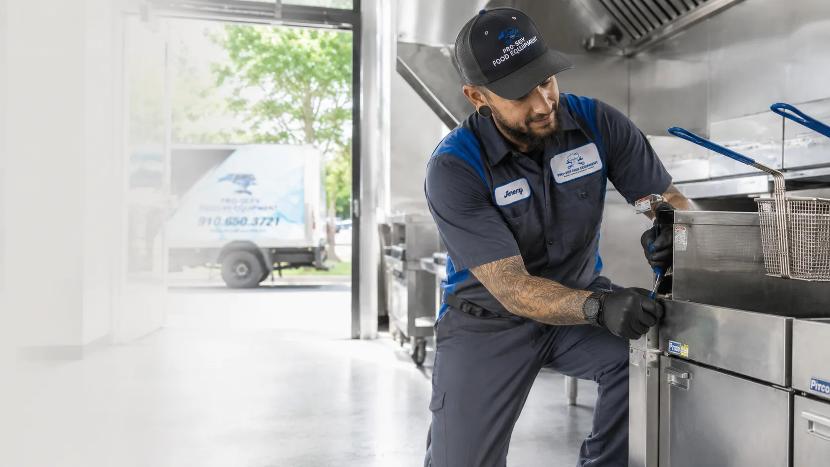 Pro-Serv Food Equipment technician servicing a commercial deep fryer with a branded service truck outside the restaurant kitchen